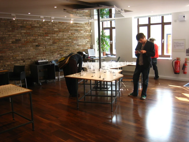 two people stand near a couple that have wine glasses on a table