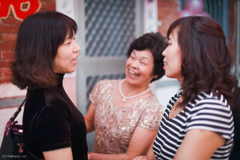 three women smiling and talking together in front of an asian restaurant