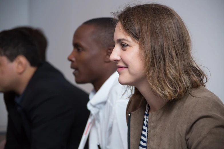 a woman sitting next to two men with their heads together