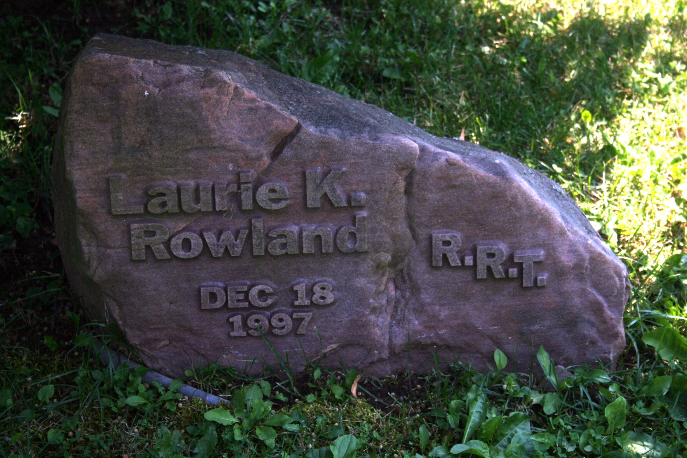 the carved name stone sits in front of the grass
