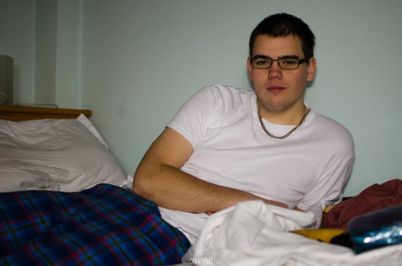 a guy in a white shirt is sitting in bed