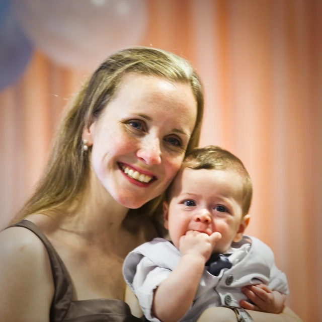 a woman holding a baby who is sitting in a chair