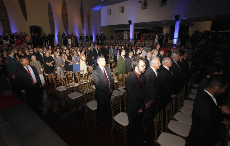 a large group of people in business suits watching an award ceremony
