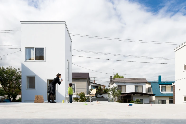 two men stand by some white buildings with a sky background