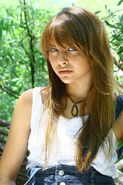 a beautiful young lady sitting under some trees