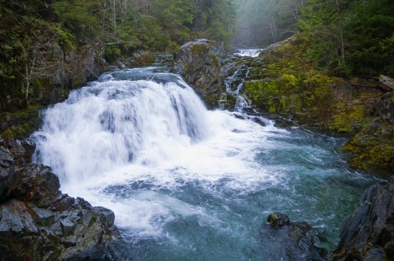 water pouring over a stone waterfall in the middle of a forest