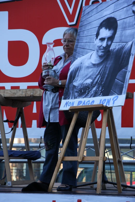 a woman stands with a large poster on an easel