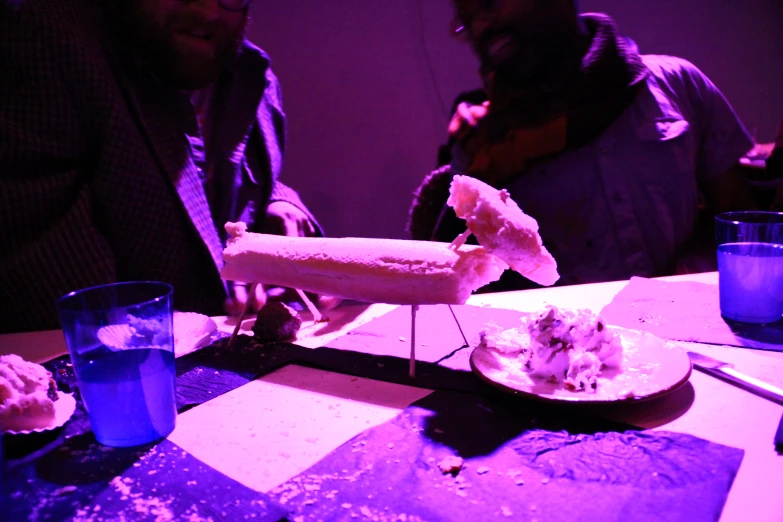 a man sitting at a table eating a large  dog