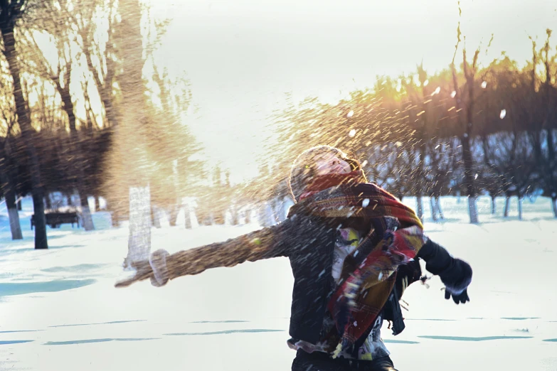 a woman is wearing a scarf and throwing snow