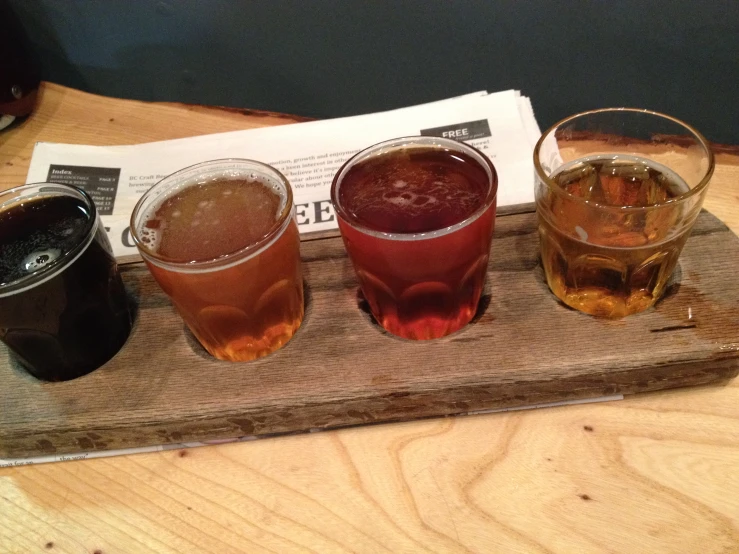 four different types of drink on a wooden tray