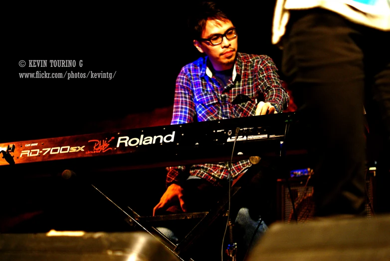 a young man wearing glasses is sitting at a keyboard