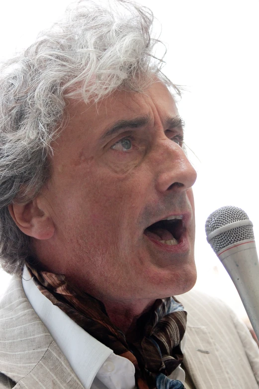 an older man singing into a microphone and wearing a suit