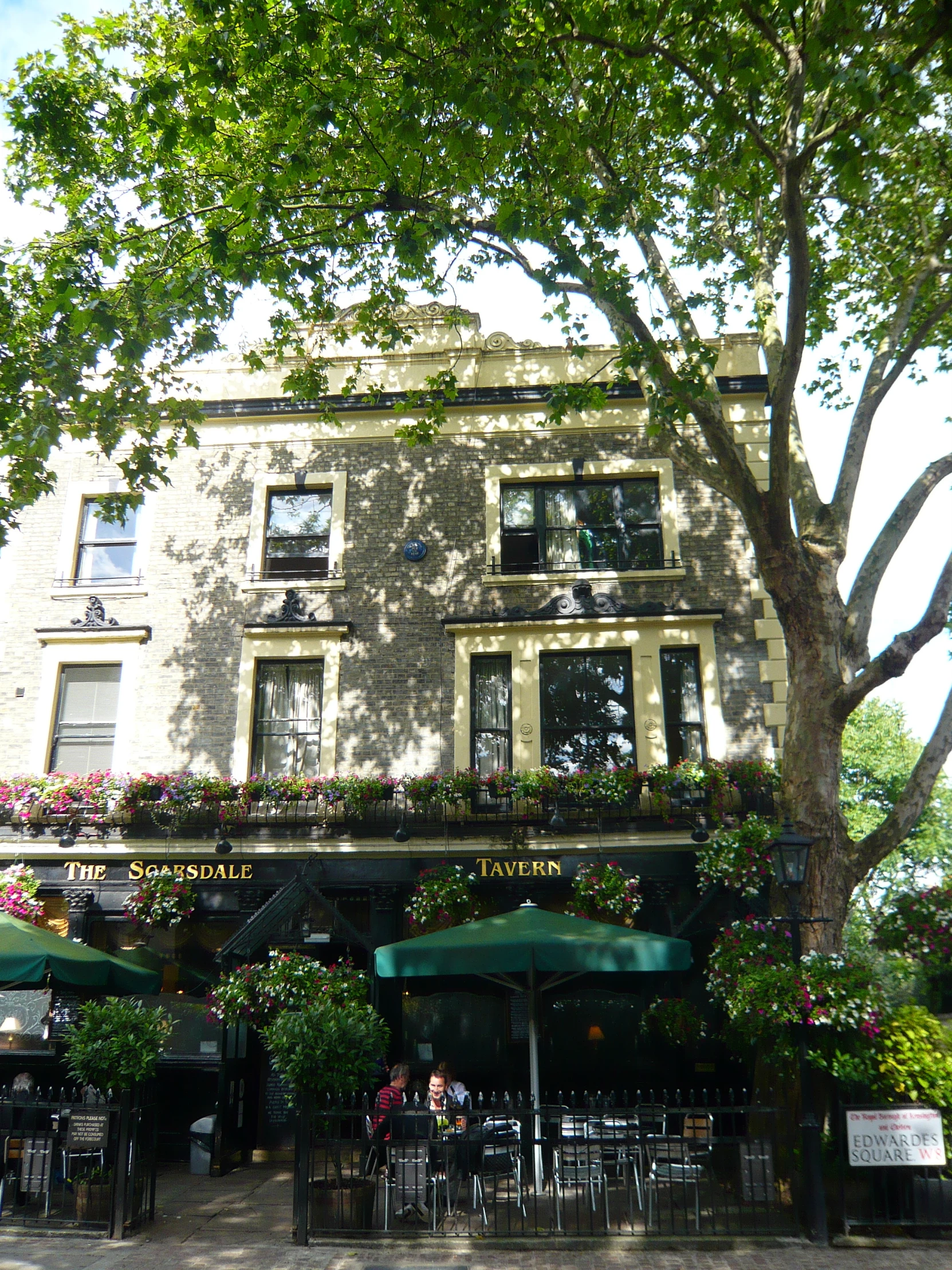 a large building with trees and lawn chairs and umbrellas