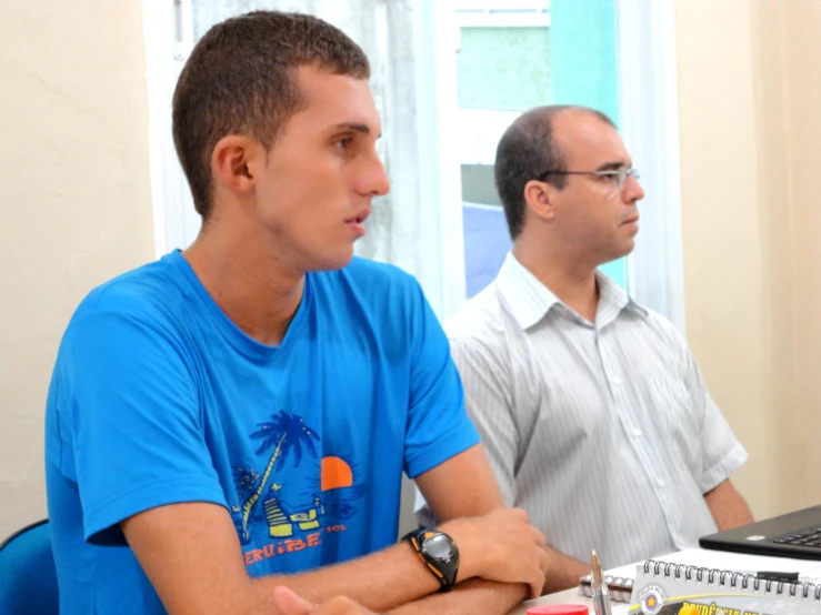 two men in front of a table with laptops