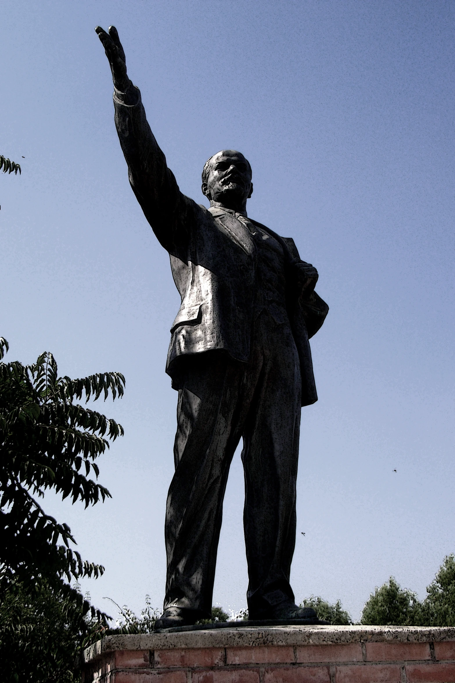 a man statue stands near some bushes