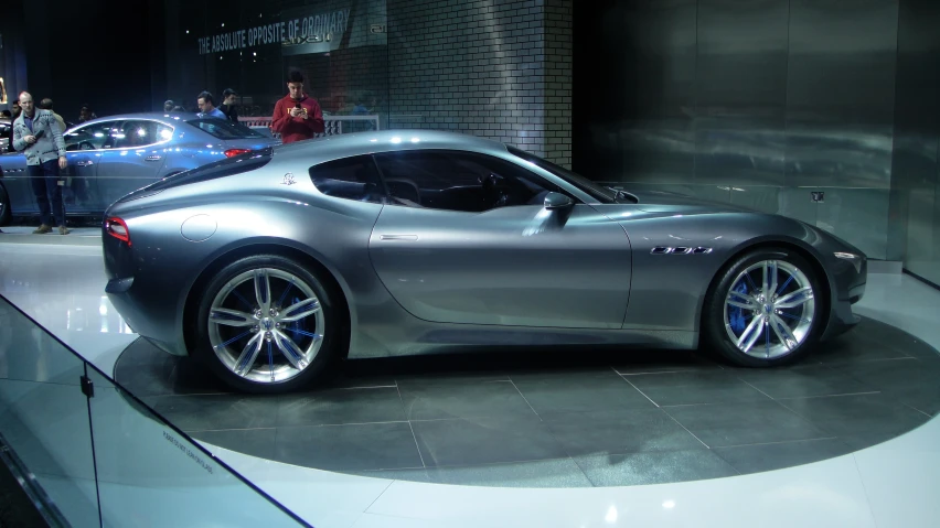 a silver sports car sitting on top of a shiny show floor