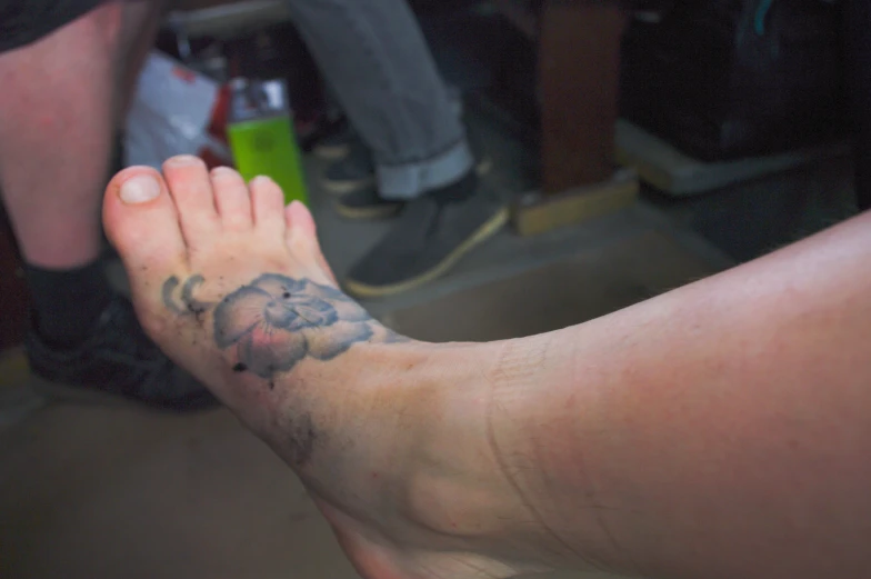 a person with a flower tattoo on their feet