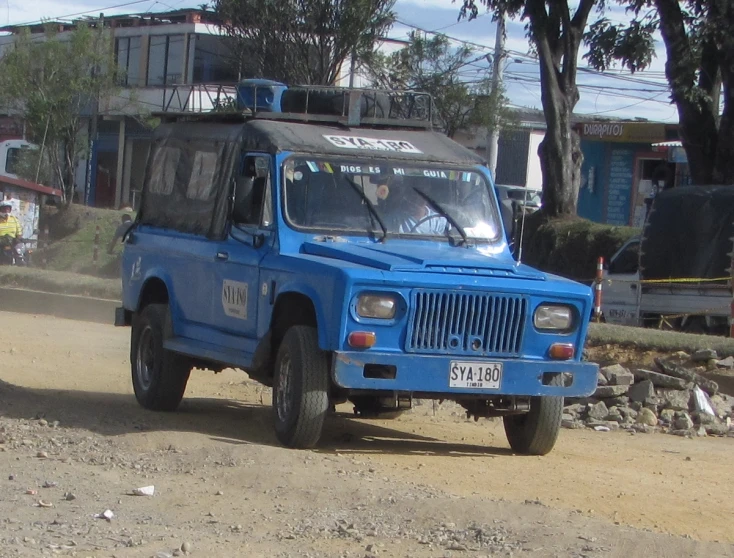 an blue truck parked on a dirt road