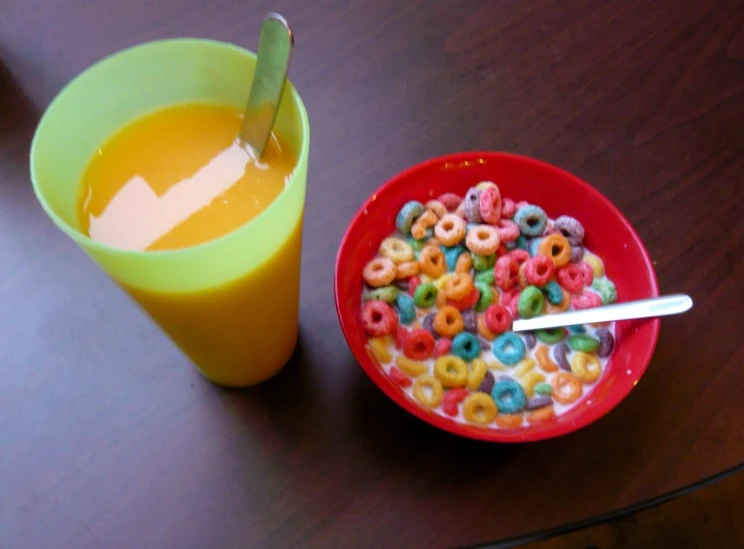 a bowl full of cereal next to an orange juice cup