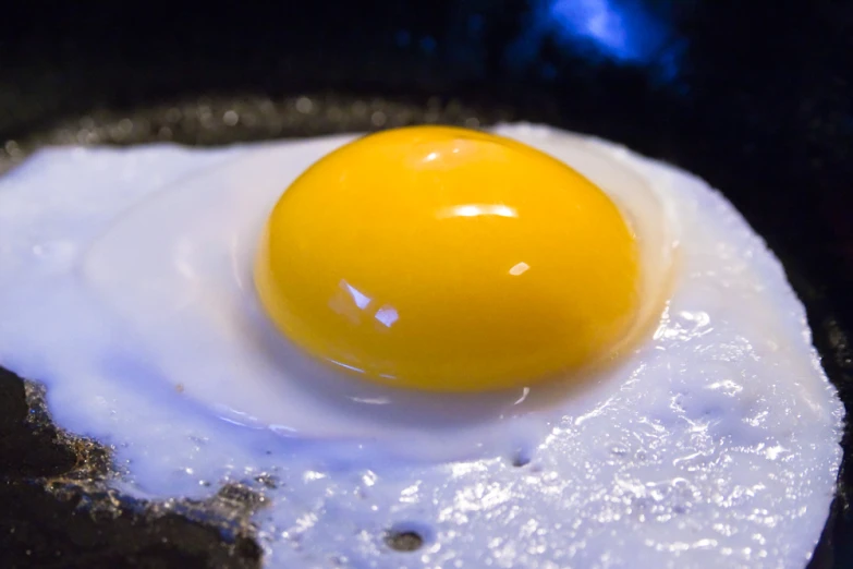 an egg that is cooking in a black frying pan