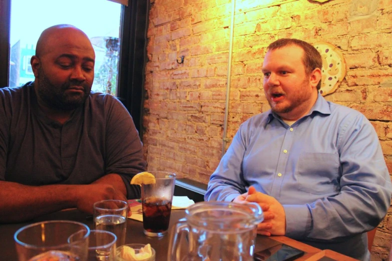 two men sitting at a table having drinks and conversation