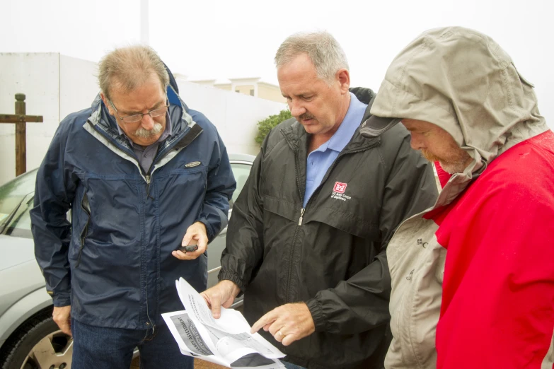 three men and one woman looking at some papers