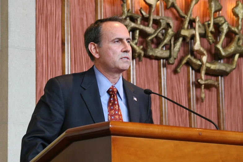 the man in a suit and tie stands at the podium