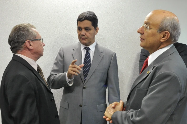 three men in suits and ties shaking hands