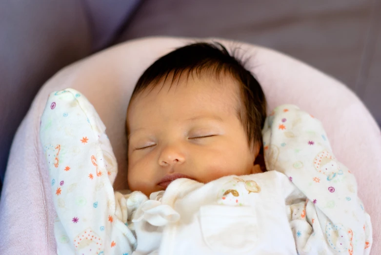 a baby sleeping in a chair holding onto a blanket