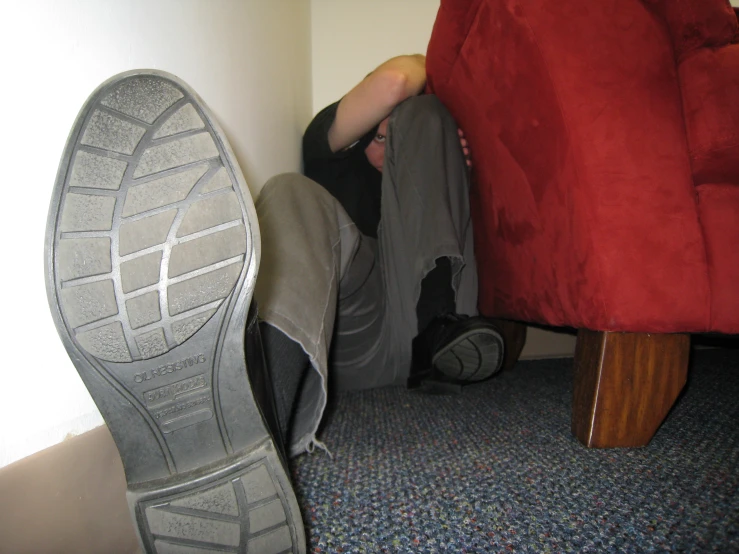 a man laying down in the corner with his feet on his foot