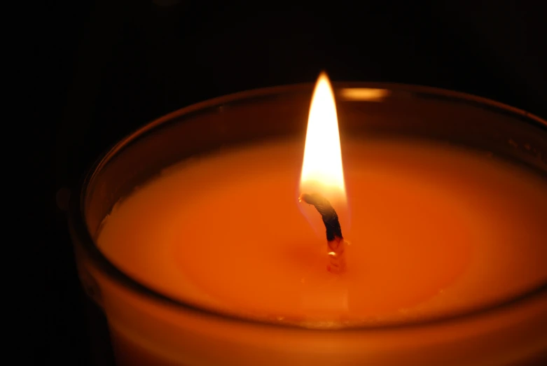 a lighted candle sitting in the middle of a dark room