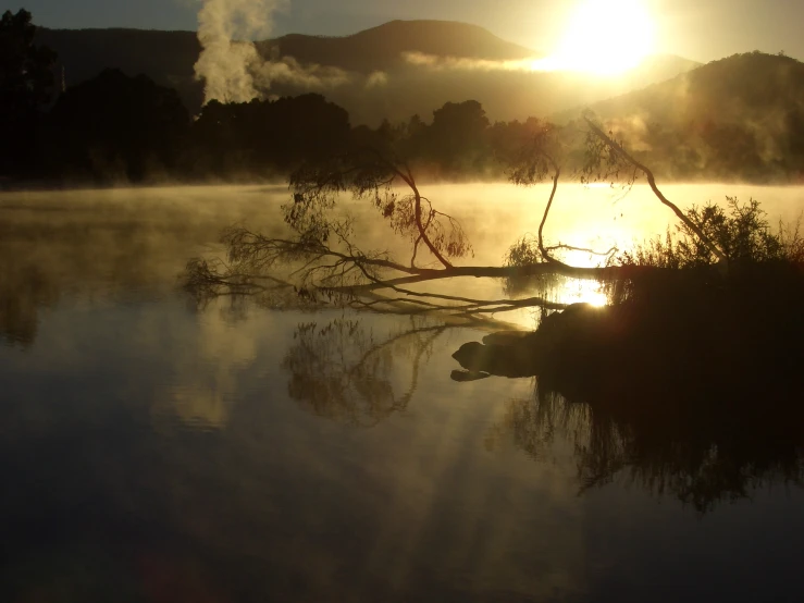 fog rising from the water with a very low mountain range behind it