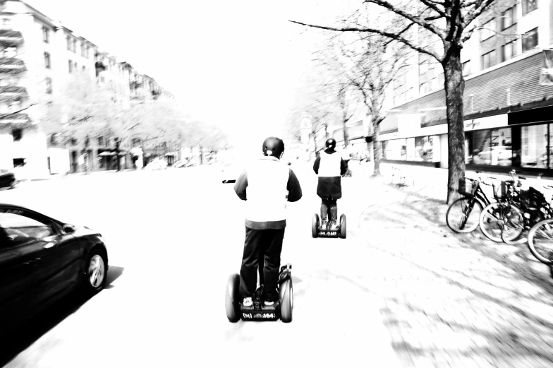 two young men ride on skateboards down a sidewalk