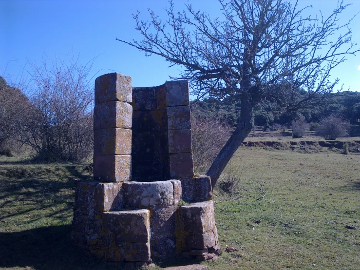 a wooden bench made out of stones on a grass covered hillside