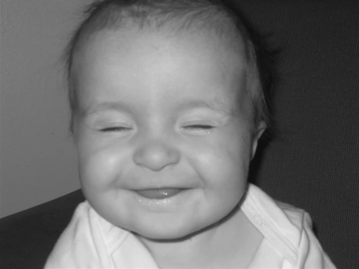 a young child is laughing and holding its head to the camera