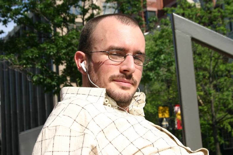 a man with ear phones in his ears looks into the camera