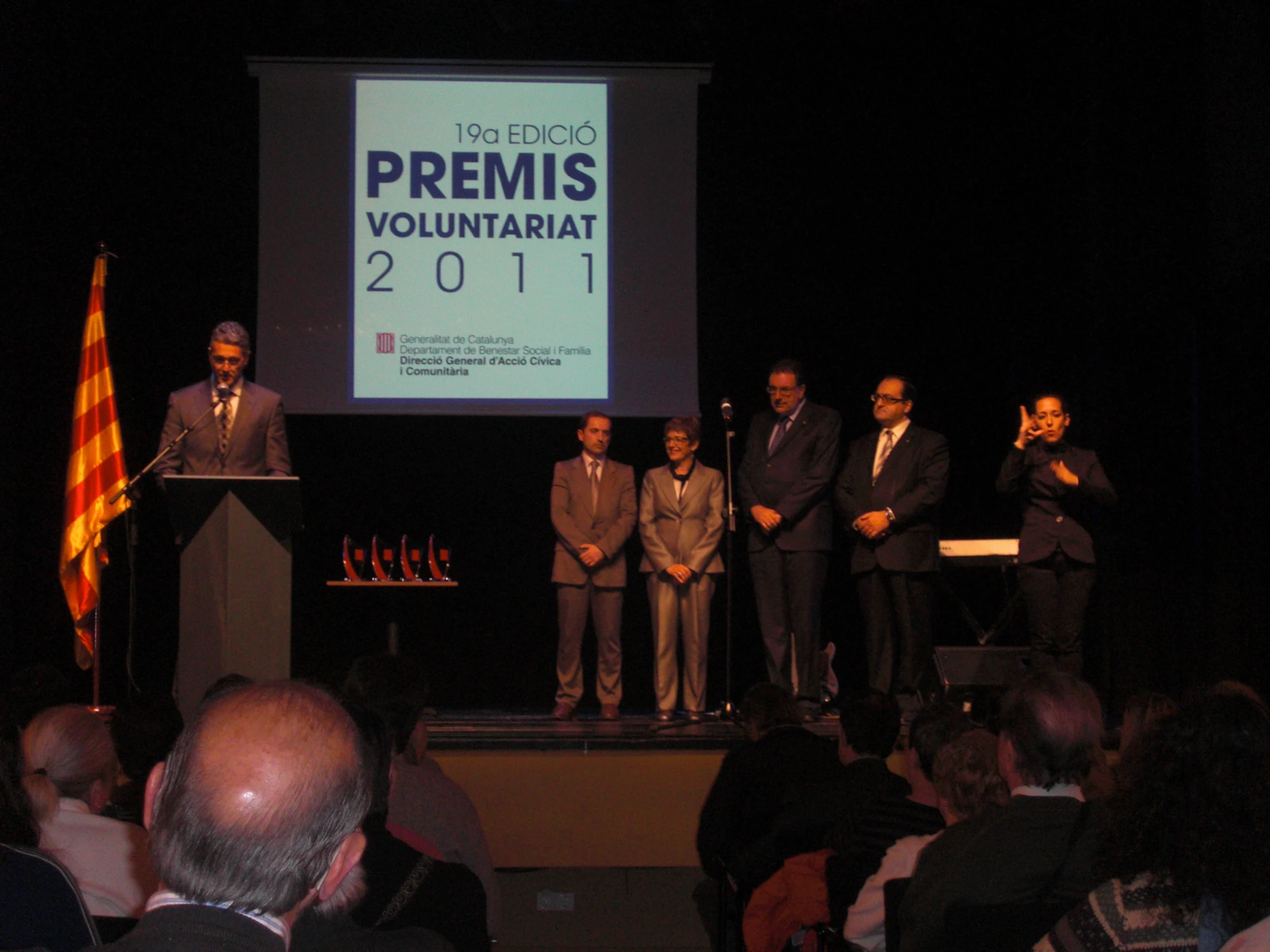 people at podium with two men standing in front of a projection screen