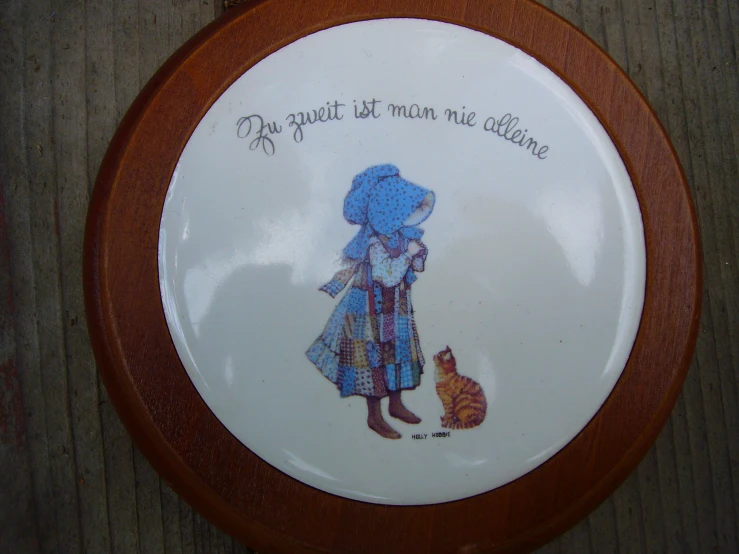 a ceramic plate on a table with a picture of a little girl and cat