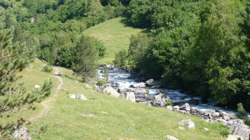 a stream is coming down a hillside in a green field