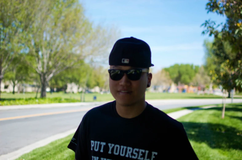 a guy is standing by the road in front of a green lawn and trees