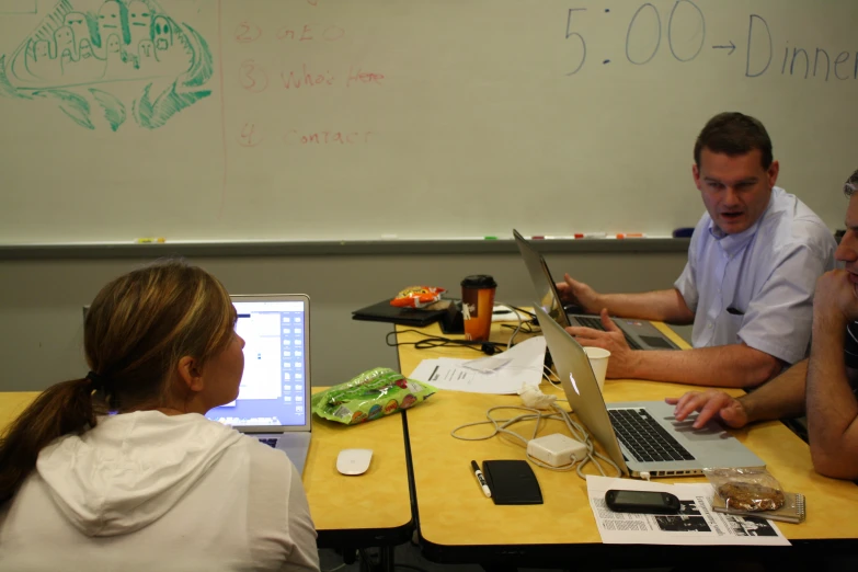 three students working together on laptops at the desk