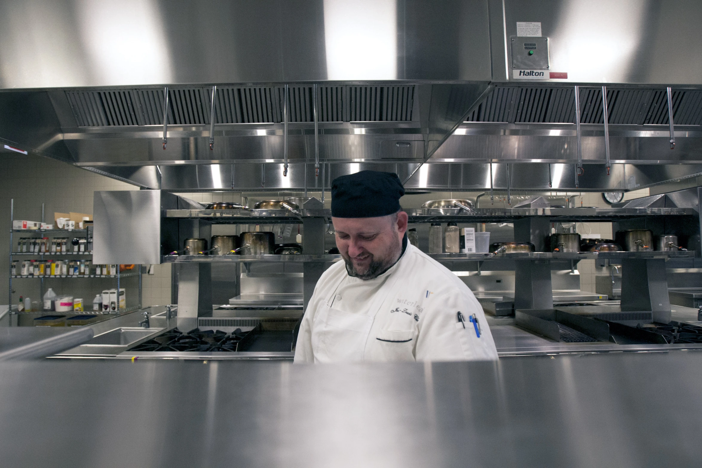 a chef wearing an apron in a large metal kitchen