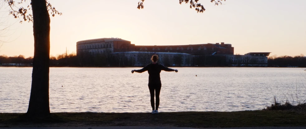 a person standing next to a body of water at sunset