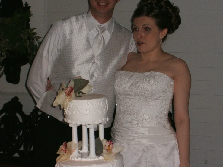 the bride and groom is smiling while holding a wedding cake