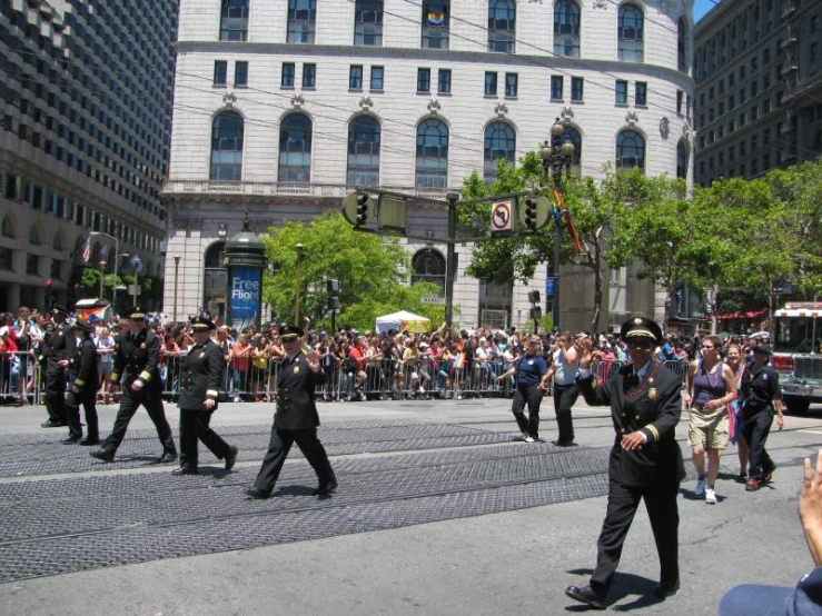 several men in black uniforms are walking in front of a building