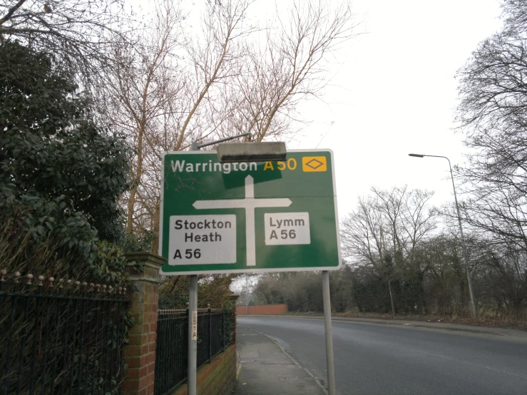 a green sign stands on a street near the side of a road