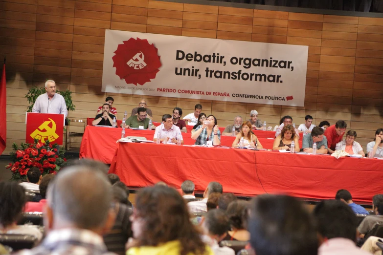 a group of people sitting around a red table