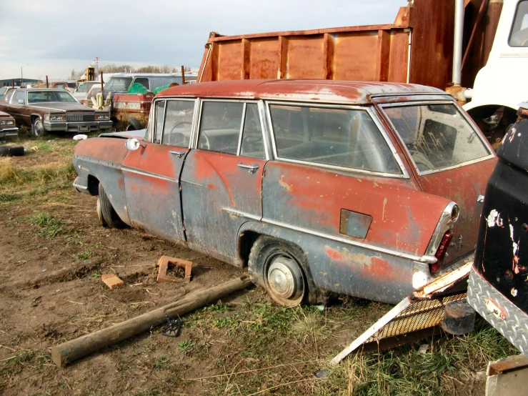an old car parked near other junkyards with it's door ajar open