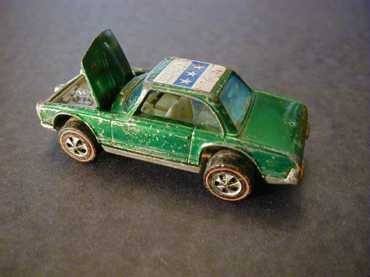 a toy green car with it's door open sitting on the floor
