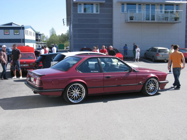 some cars parked in a parking lot with people looking at them